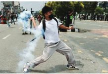 Nepal’s Gen Z protests against corruption, social media ban A young man wearing a white t-shirt, rucksack, jogging bottoms and Nike trainers, appears to throw what looks like a smoke shell towards riot police on a road in Kathmandu. REUTERS