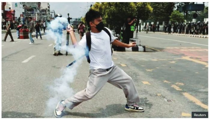 Nepal A young man wearing a white t-shirt, rucksack, jogging bottoms and Nike trainers, appears to throw what looks like a smoke shell towards riot police on a road in Kathmandu. REUTERS