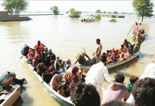 People packed onto small boats floating in brown flood waters in Pakistan. Rescuers have to go door-to-door to relocate villagers by boats. GETTY IMAGES