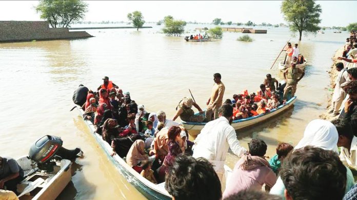 Pakistan People packed onto small boats floating in brown flood waters in Pakistan. Rescuers have to go door-to-door to relocate villagers by boats. GETTY IMAGES