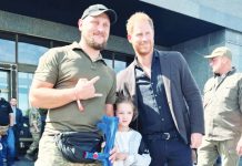 Prince Harry poses for a picture with a Ukrainian serviceman and a small girl outside a museum in Kyiv. REUTERS