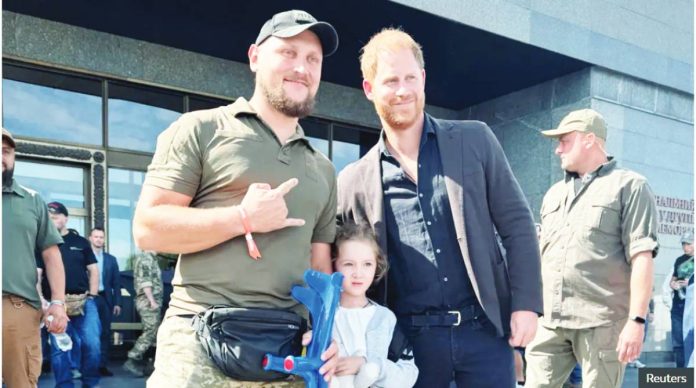 Ukraine Prince Harry poses for a picture with a Ukrainian serviceman and a small girl outside a museum in Kyiv. REUTERS