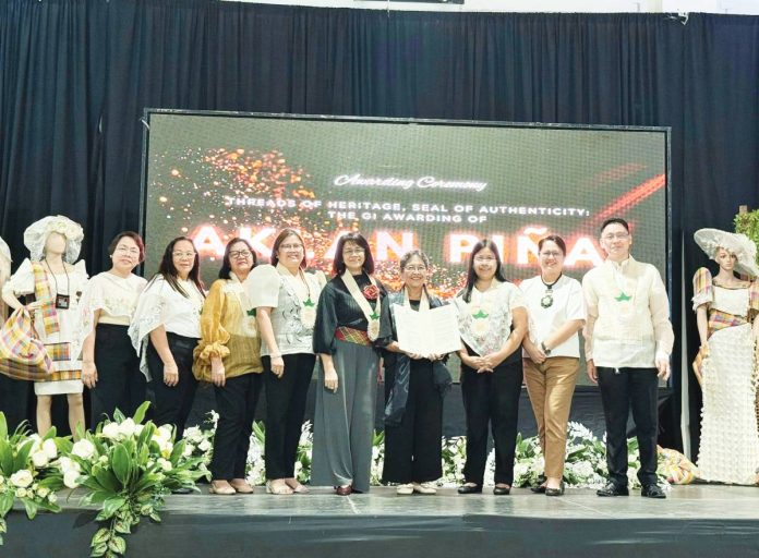 Anna India Legaspi (center), president of the Aklan Piña & Indigenous Fibers Manufacturers and Traders Association, Inc. (Aklan Piña Mantra), receives the Certificate of Geographical Indication (GI) Registration for Aklan piña during the awarding ceremony held on September 19 in Kalibo, Aklan. DTI-6 PHOTO