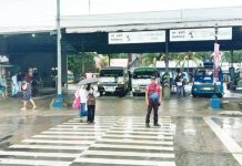 Intermittent rains forced the suspension of in-person classes in Iloilo City schools on Monday, Sept. 22, 2025. Photo shows a traffic enforcer assisting two students crossing the pedestrian lane in front of a transport terminal in Barangay Ungka, Jaro district during rainy Monday morning. ICTTMO PHOTO