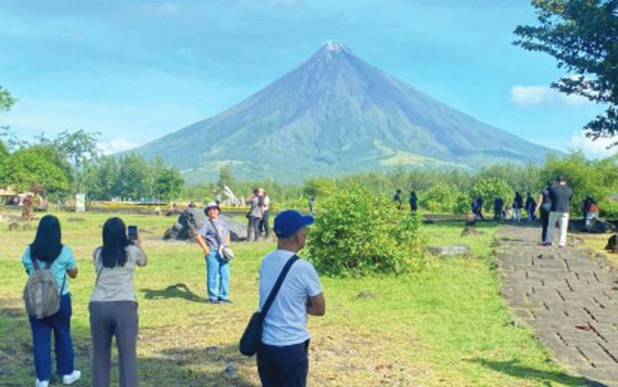 tourism_contribution_resized Tourists enjoy the clear view of Mayon Volcano in Cagsawa Ruins in Daraga, Albay province on Feb. 1, 2025. The Department of Tourism on Tuesday, Sept. 2, told a congressional budget hearing that the tourism sector is projected to generate P2.7 trillion for the Philippine economy this year. PNA FILE PHOTO BY CONNIE CALIPAY