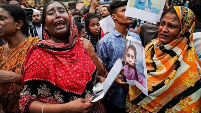 Bangladesh.JPG_resized Two tearful women in the foreground hold on to photographs of their loved ones printed on paper. A larger crowd has gathered behind them, many of them also clutching onto photographs of their relatives still missing after a fire blazed through a garment factory in Bangladesh. GETTY IMAGES