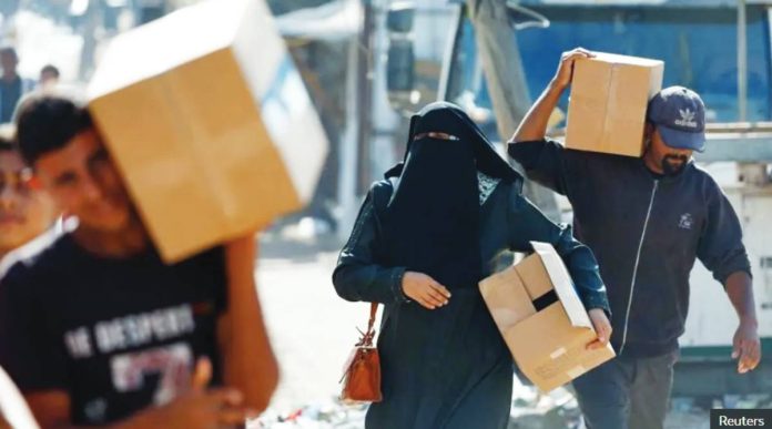 Gaza Palestinians carry aid supplies that entered Gaza, amid a ceasefire between Israel and Hamas in Gaza. REUTERS