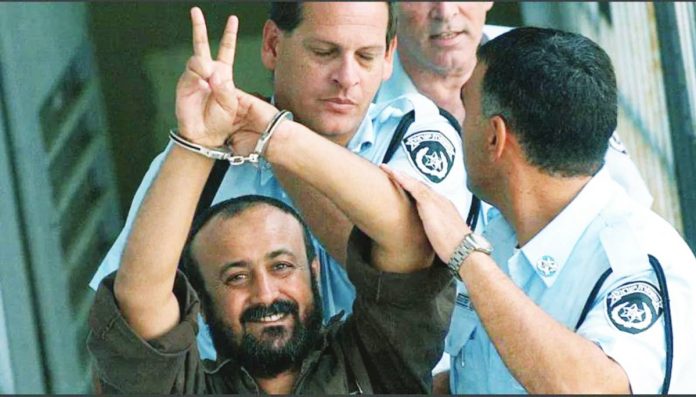Hamas copy Marwan Barghouti is hand cuffed and flashing the V-sign as he is led to a police vehicle by police officers wearing blue shirts. He was convicted of deadly attacks on Israeli civilians, but remains one of the most popular Palestinian leaders. AFP VIA GETTY IMAGES