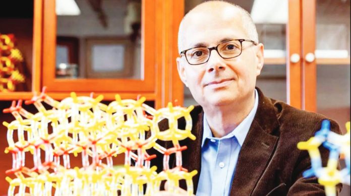 Nobel Chem Chemistry professor Omar Yaghi poses in his lab at the University of California in Berkeley US. Next to him is a model showing metal-organic frameworks made of yellow and red tubes and nodes. REUTERS