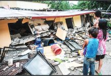 People look stunned standing before a collapsed building in Bogo City, Cebu, on Wednesday, October 1, 2025 after an offshore earthquake on late Tuesday. AP