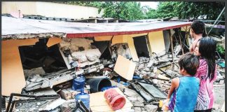 People look stunned standing before a collapsed building in Bogo City, Cebu, on Wednesday, October 1, 2025 after an offshore earthquake on late Tuesday. AP