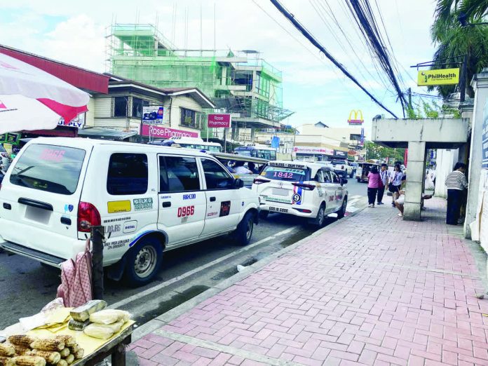 ILONGGO DRIVERS ON EDGE. The looming rollout of “blue taxi” units in Iloilo City has local taxi operators and drivers worried about losing passengers. Photo shows taxi units waiting for passengers in front of a hospital on E. Lopez Street, Jaro, Iloilo City, on Monday afternoon, Oct. 27, 2025. MAI LADIAO/PN
