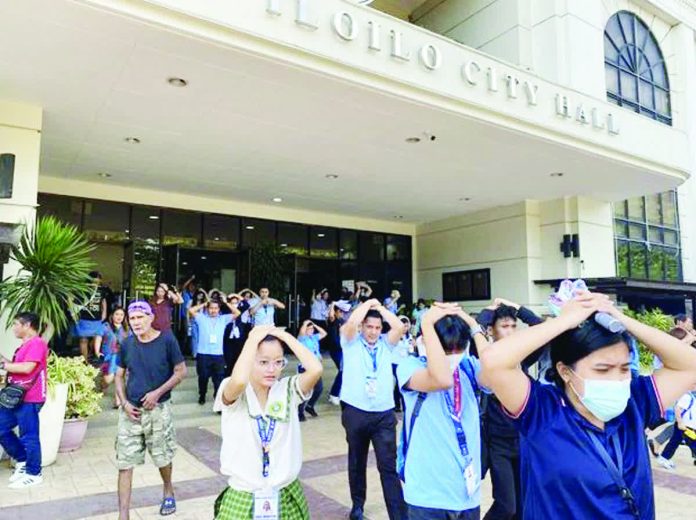 Iloilo City Government personnel evacuate the city hall with their hands on their heads during the region-wide earthquake and tsunami drill on Thursday, October 23, 2025. The exercise simulated the “duck, cover, and hold” maneuver followed by an organized evacuation to ensure readiness in case a major seismic event strikes the region. GIL CONDES PHOTO