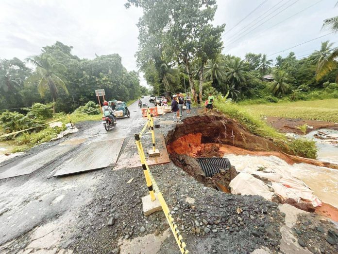 Sigma, Capiz’s Mayor Dante Eslabon, along with local public works officials, inspects the flood-damaged road in Barangay Ibia-an, Mianay, Sigma, where a large sinkhole has rendered the area impassable to vehicles. PHOTO FROM THE MUNICIPALITY OF SIGMA