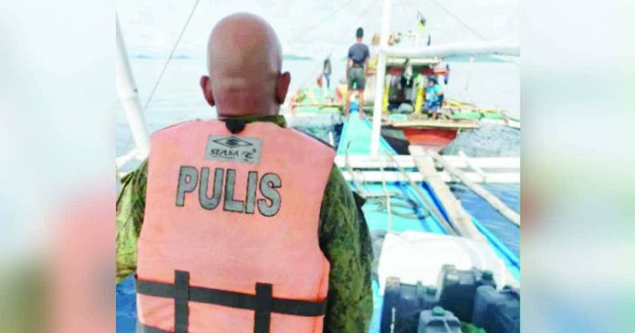 neljoy banca copy_superimposed_compressed A police officer from the Iloilo Provincial Mobile Force Company joins the Bantay Dagat Task Force in intercepting a motor banca engaged in illegal fishing during a seaborne operation off northern Iloilo. PHOTO FROM ILOILO POLICE PROVINCIAL OFFICE