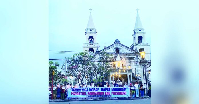 neljoy silent protest (1)_superimposed Wearing determination instead of anger, parishioners and altar servers gather outside the Jaro Metropolitan Cathedral in Iloilo City for a silent protest organized by “Kahublagan Kontra Korapsyon” on October 25, calling for accountability and justice for those involved in government corruption. Their banner reads, “Tanan nga korap, dapat manabat! Pasabton, pabayaron kag presohon!” — a demand for integrity in public service. KAHUBLAGAN KONTRA KORAPSYON PHOTO