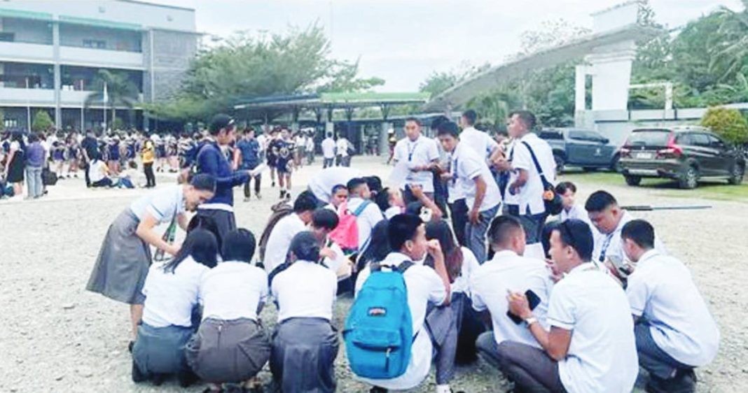 quake2.JPG_resized High school students huddle on the ground outside their school in Davao Oriental after feeling the magnitude 7.4 earthquake.