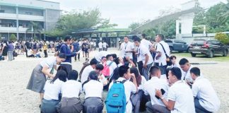 High school students huddle on the ground outside their school in Davao Oriental after feeling the magnitude 7.4 earthquake.
