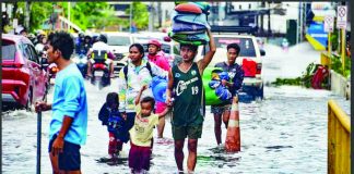Residents carrying their belongings, wade through a flooded street in Mandaue City, Cebu province. They are assessing damage after Typhoon Tino. AFP VIA GETTY IMAGES