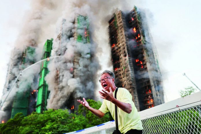 HK_fire1_resized_compressed A man screams in anguish while a massive blaze consumes multiple high-rise blocks at the Wang Fuk Court housing estate in Tai Po, Hong Kong, on Nov. 26, 2025. Authorities later confirmed over 40 fatalities and hundreds unaccounted for in one of the city’s deadliest fires in recent years. The Philippines’ Department of Foreign Affairs says the Philippine Consulate General in Hong Kong received unverified information that some Filipino domestic workers may be trapped inside the buildings. REUTERS PHOTO