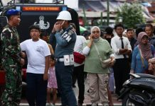 A police officer speaks to an army officer following an explosion at a mosque as members of the public watch on. REUTERS