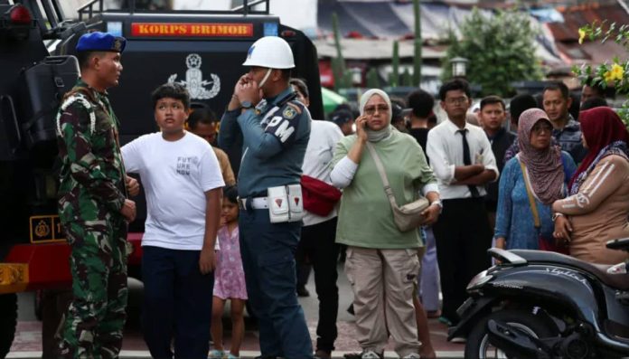 Indonesia_compressed A police officer speaks to an army officer following an explosion at a mosque as members of the public watch on. REUTERS