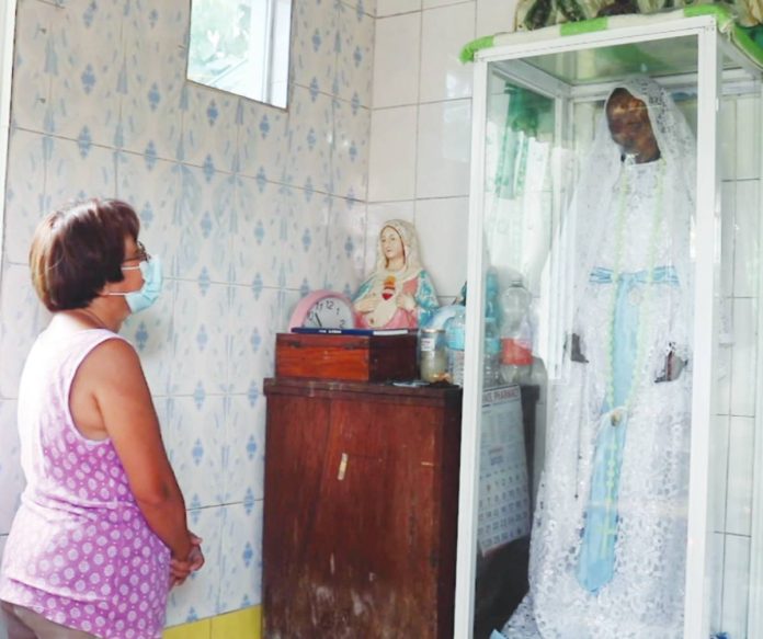 A local devotee offers a silent prayer before the preserved remains of Maria “Lola Ibe” de Juan Basañes inside a small shrine in Barangay Casanayan, Pilar, Capiz — a place revered for faith and miracles. PHOTO FROM: I JUANder
