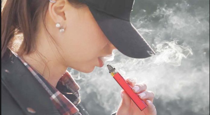 UK-copy A young woman draws on a vape or e-cigarette while the vapor blows around her mouth and face. GETTY IMAGES