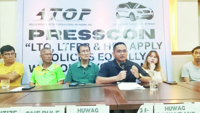 ime_blue_resized_compressed Atty. Bjorn Denfield Hudierez (4th from left), legal counsel of local taxi operators in Panay Island, speaks during a press conference calling on the Land Transportation Franchising and Regulatory Board and the Land Transportation Office to act on the operators’ complaints regarding the operation of newcomer blue taxis. With him are officials of local taxi alliances.