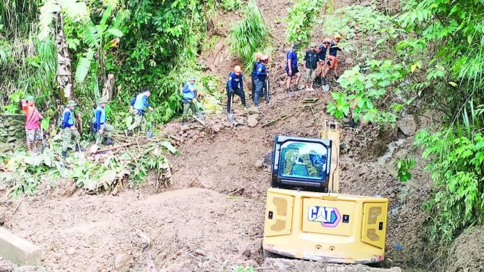 Rescuers from the police, military, and fire bureau coordinate efforts with local volunteers as a backhoe clears debris at the landslide site in Barangay Barasalon, Janiuay, Iloilo, where a resident was believed buried following days of rain. AJ PALCULLO/PN