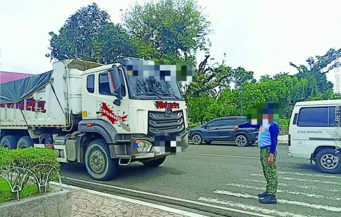 nelloy_quarry_resized_compressed A police officer flags down a dump truck during a simultaneous operation against illegal quarrying in Iloilo Province on November 8, 2025. Four trucks were seized in New Lucena and Santa Barbara towns for lacking valid delivery receipts and carrying tampered documents. PHOTO COURTESY OF IPPO