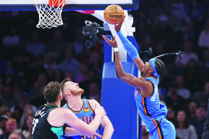sports_NBA_copy_resized_compressed Oklahoma City Thunder guard Shai Gilgeous-Alexander shoots next to Portland Trail Blazers center Donovan Clingan and Thunder center Isaiah Hartenstein. AP
