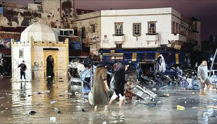 People wade through floodwaters in the old city center of Morroco. AFP VIA GETTY IMAGES