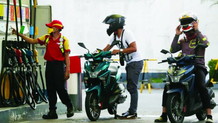 A gasoline station attendant in Quezon City assists motorcycle riders as vehicle owners start queuing to fill their tanks. Fuel prices are expected to go down next week ahead of the Christmas break. LYN RILLON/INQUIRER.NET FILE PHOTO