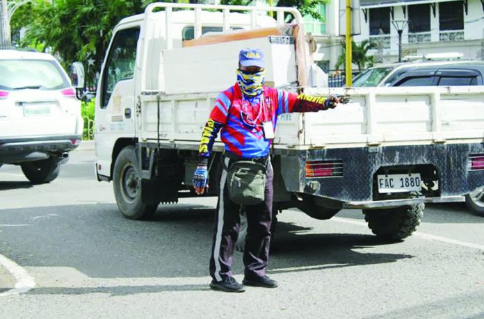 A traffic enforcer directs vehicles amid moderate congestion along Bonifacio Drive and General Luna Street in Iloilo City, as traffic builds up near major commercial establishments ahead of the expected surge of holiday shoppers and motorists. AJ PALCULLO/PN