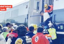 Rescuers gather at a derailed train as a wounded is being helped from a carriage. BBC