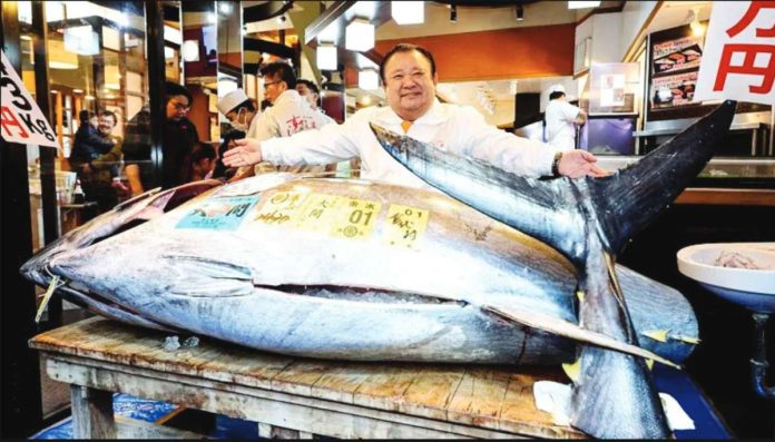 Tokyo A man spreads his arms over a giant tuna laying on a table at Tokyo, Japan’s Toyosu fish market. GETTY IMAGES