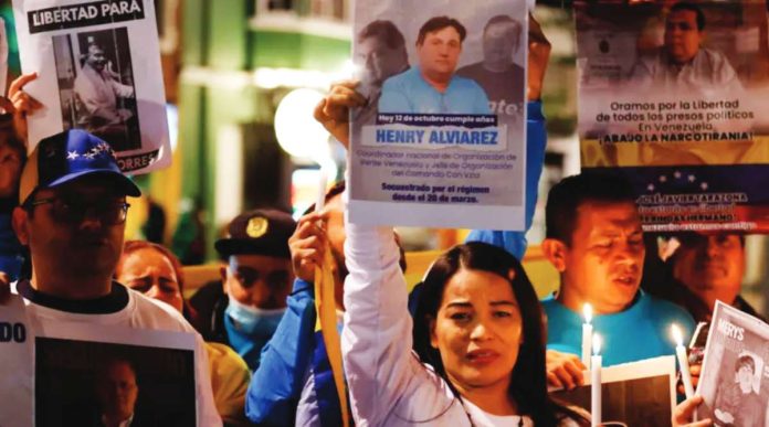 A group of protesters with a woman centered hold candles and signs of people who have been made political prisoners in Venezuela. EPA