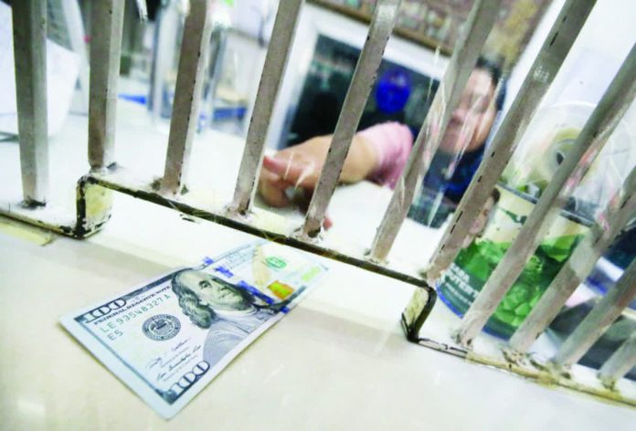 peso_dollar_resized_compressed An employee at a money exchange shop on A. Mabini Street in Manila accepts a hundred-dollar bill from a customer so it can be converted into pesos. Photo by LYN RILLON / Philippine Daily Inquirer