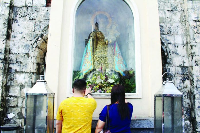 Devotees pause in silent prayer before the image of Nuestra Señora de la Candelaria at her outdoor niche in the Jaro Metropolitan Cathedral, offering petitions and thanksgiving in an intimate moment of faith. AJ PALCULLO/PN