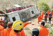 A bus lies on its side, surrounded by emergency workers in Brazil. GOVERNMENT OF ALAGOAS