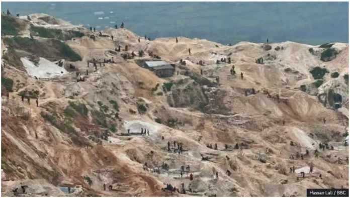 Overhead shot of mining activities at Rubaya mine where the terrain is hilly - slightly terraced. Many groups of miners can be seen from a distance cleaning ore. Hassan Lali / BBC