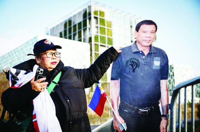 A person stands by a life-size cartboard cutout of former Philippine president Rodrigo Duterte during a demonstration outside the International Criminal Court in The Hague, Netherlands. AFP