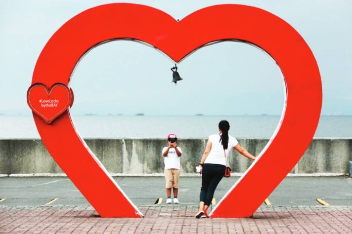 SWS A heart-shaped arch is an instant hit for a woman and her son near Manila Bay in Pasay City, just a few days before Valentine’s Day. INQUIRER FILE PHOTO