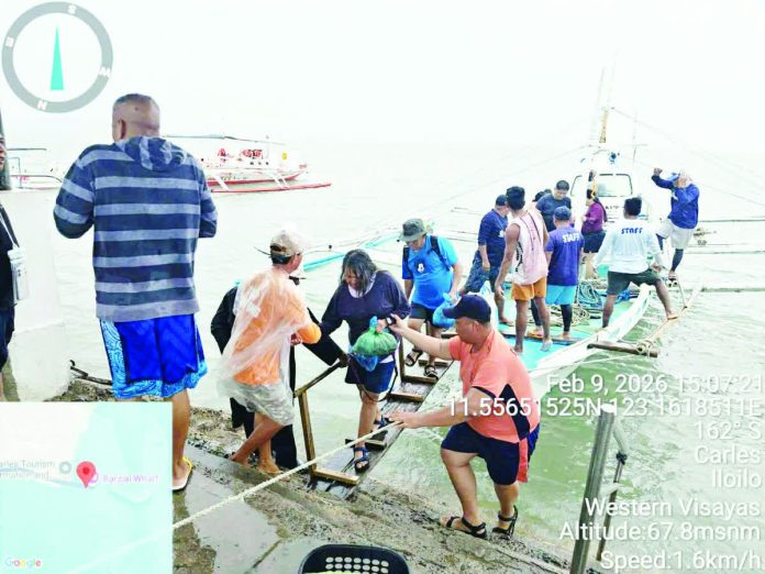 ime_sakayan_copy_resized_compressed Passengers are assisted ashore after being rescued from a capsized motorized banca off Barangay Buenavista, Carles, Iloilo, following rough sea conditions while en route to Gigantes Island. All 17 passengers and crew members were safely brought to Bancal Wharf and later checked by health personnel. PHILIPPINE COAST GUARD PHOTO