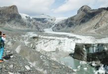 A scientist takes a photo as part of an annual monitoring project of Austrian glaciers administered by the Austrian Alpine Association. In the background are glacier slopes down the rocky mountainside, while in the foreground chunks of ice are in a stream. GETTY IMAGES