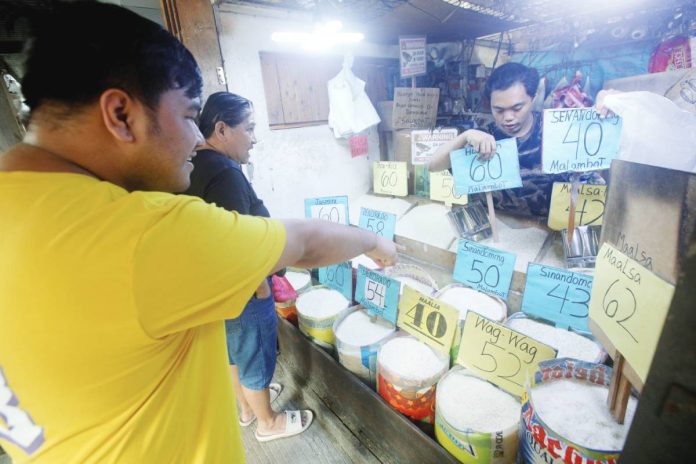 Customers buy rice priced from P40 to P65 per kg. at a stall at the Paco Public Market in Manila. The Department of Agriculture is considering a P50-per-kg. price cap on imported rice to temper rising costs, with prices in some markets reaching P60 to P65 due to higher freight rates linked to the Middle East conflict. PNA