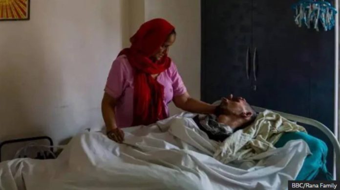 Harish Rana’s mother pats him lying in a bed. Rana has been in a vegetative state since 2013 after falling from a fourth-floor balcony. BBC/RANA FAMILY