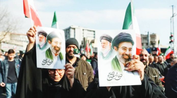 People in Tehran hold placards with an image of Iran’s new supreme leader Mojtaba Khamenei with late Iranian Supreme Leader Ayatollah Ali Khamenei. WANA/REUTERS