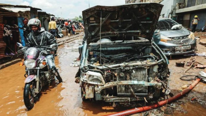 Kenya A man rides a motorbike through brown floodwater next to a damaged car after it was swept away by floods at Grogon garage area, known for automotive workshops and auto spares along the banks of the Nairobi River in downtown Nairobi, Kenya. EPA